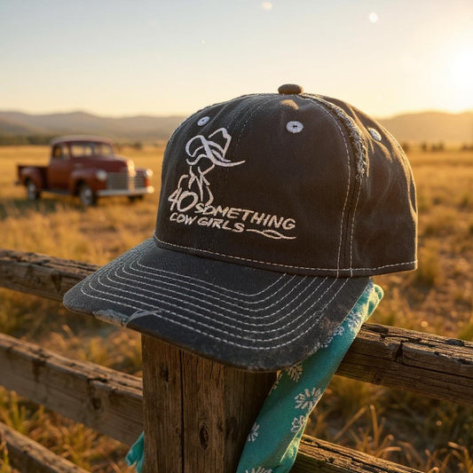 Navy cap with '40 Something Cowgirls' text on a wooden post with a sunset and truck in the background